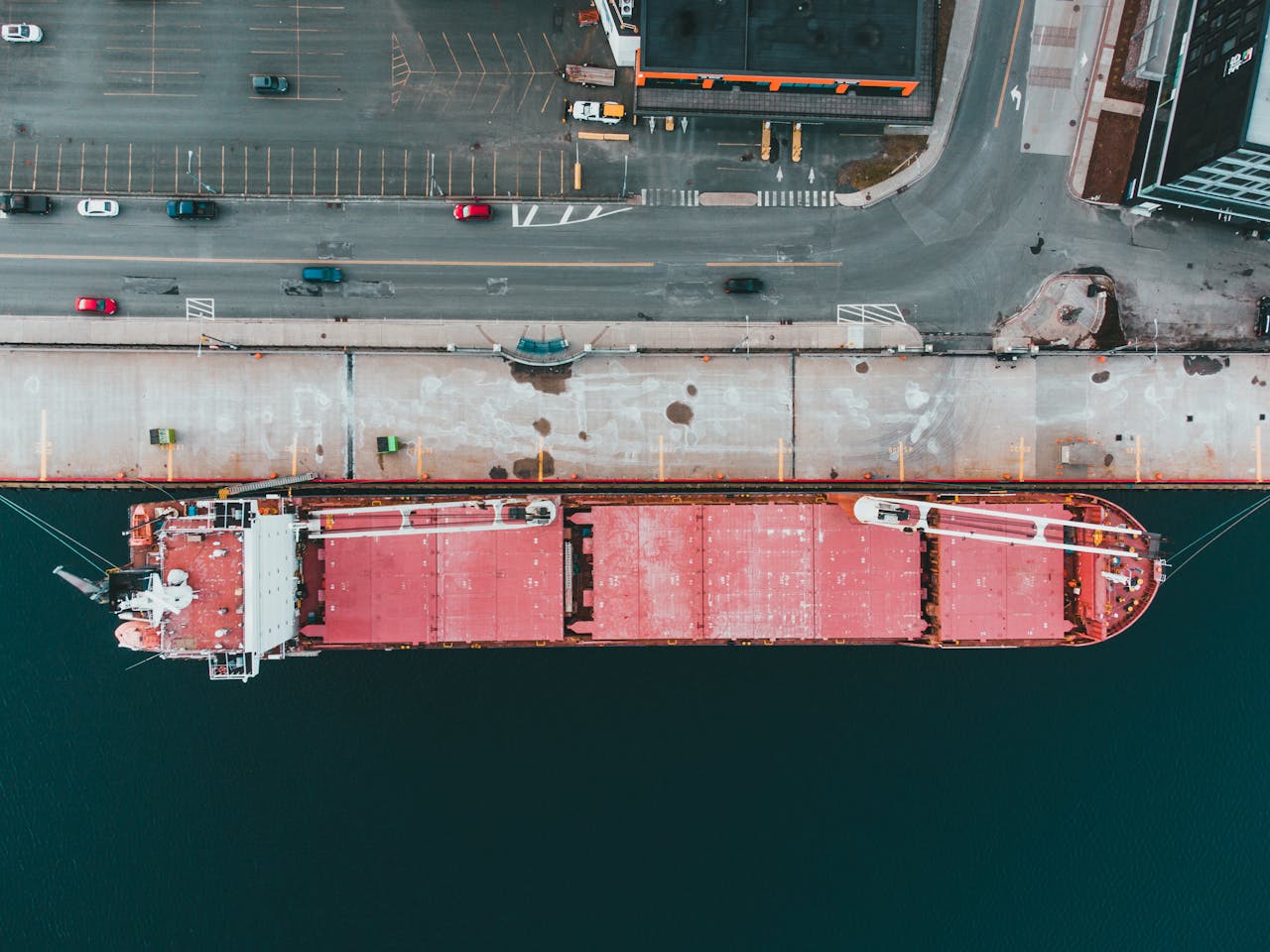 Overhead shot of a large cargo ship moored at a bustling urban port, showcasing industrial logistics.